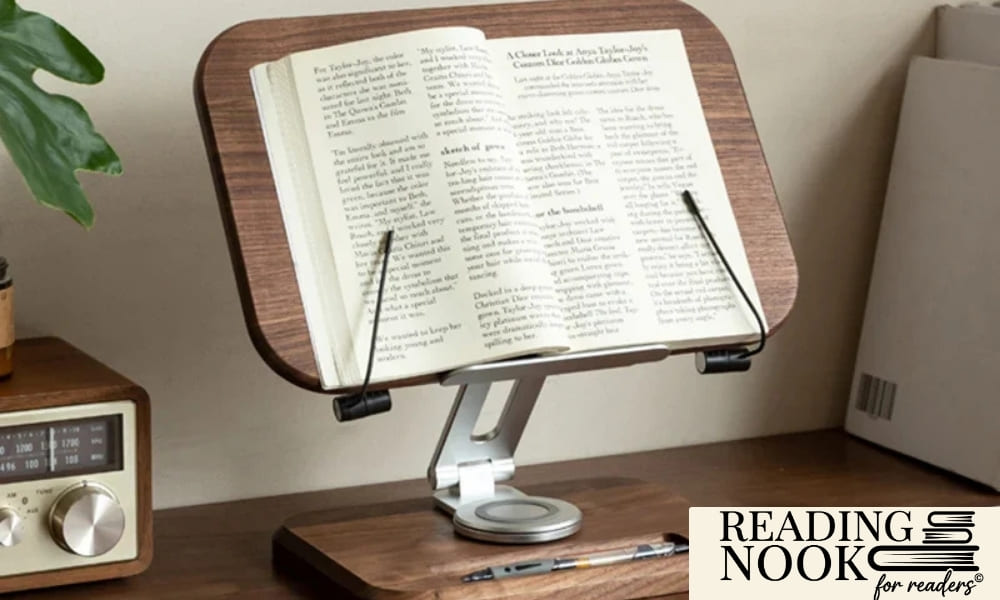 An ergonomic adjustable book stand made of dark walnut wood and aluminum, holding an open book with flexible page clips. The stand is placed on a wooden desk next to a vintage radio and a cup of coffee, creating a cozy and organized study nook aesthetic
