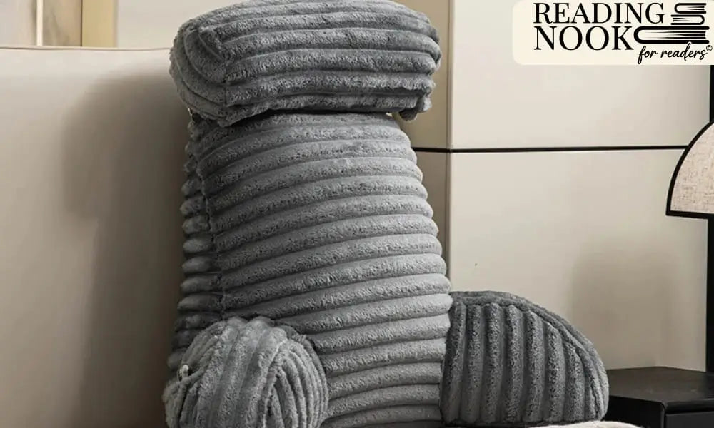A supportive grey reading pillow made of plush ribbed corduroy fabric. The pillow features comfortable armrests and a detachable cylindrical headrest for neck support, designed as a backrest for sitting up in bed or on a sofa
